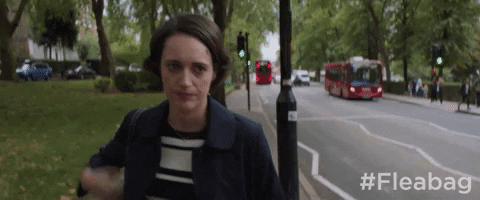 fleabag walking down the road looking rough smoking a cigarette