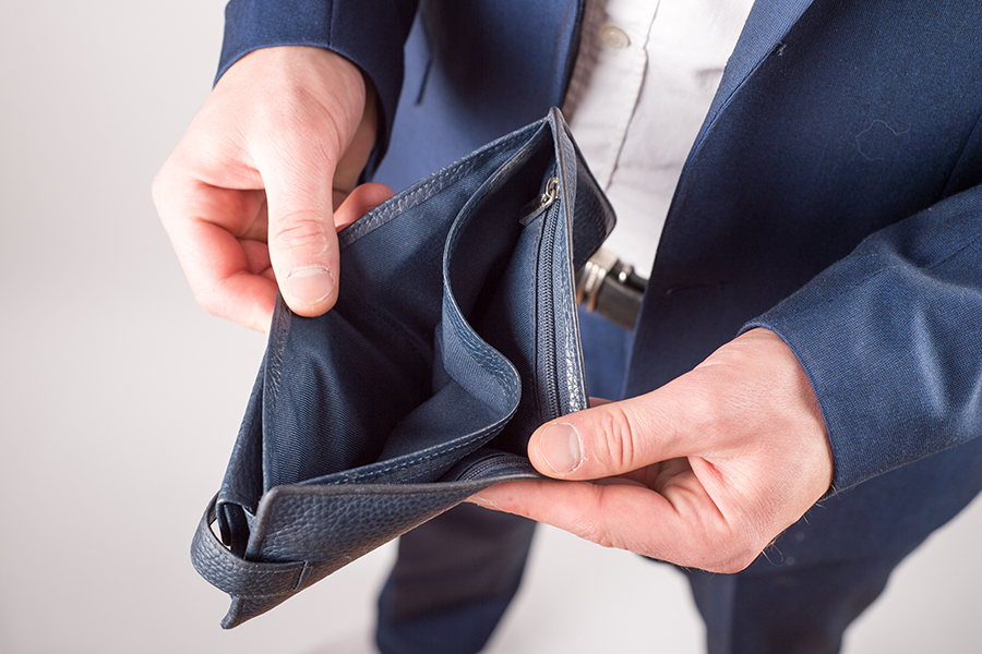 A man wearing a navy blue suit opens an empty wallet.