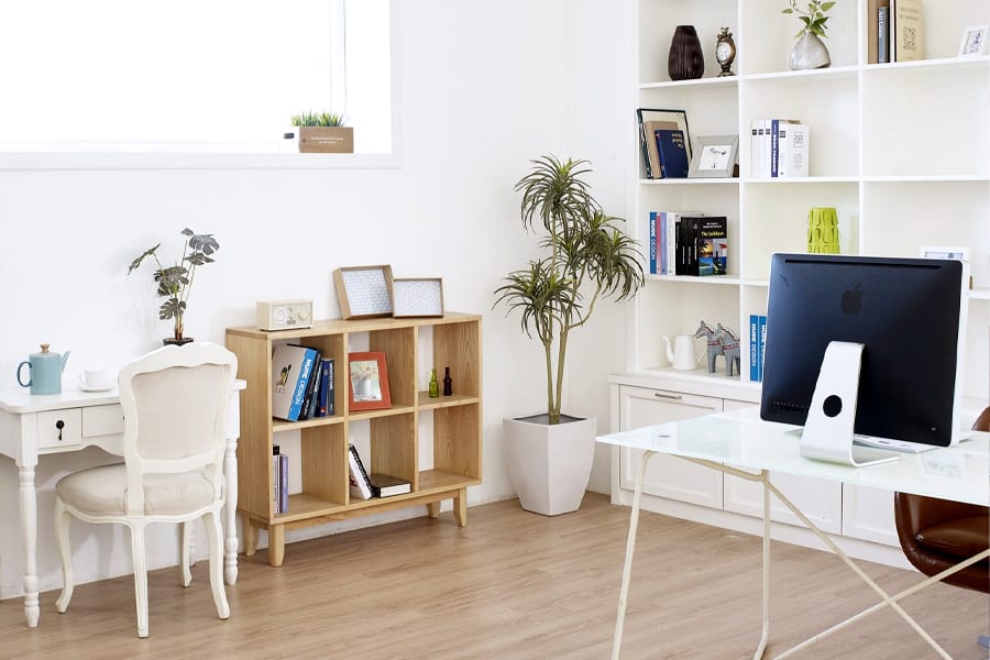 A living room with white walls and eclectic decor has an iMac sitting on a white computer desk.