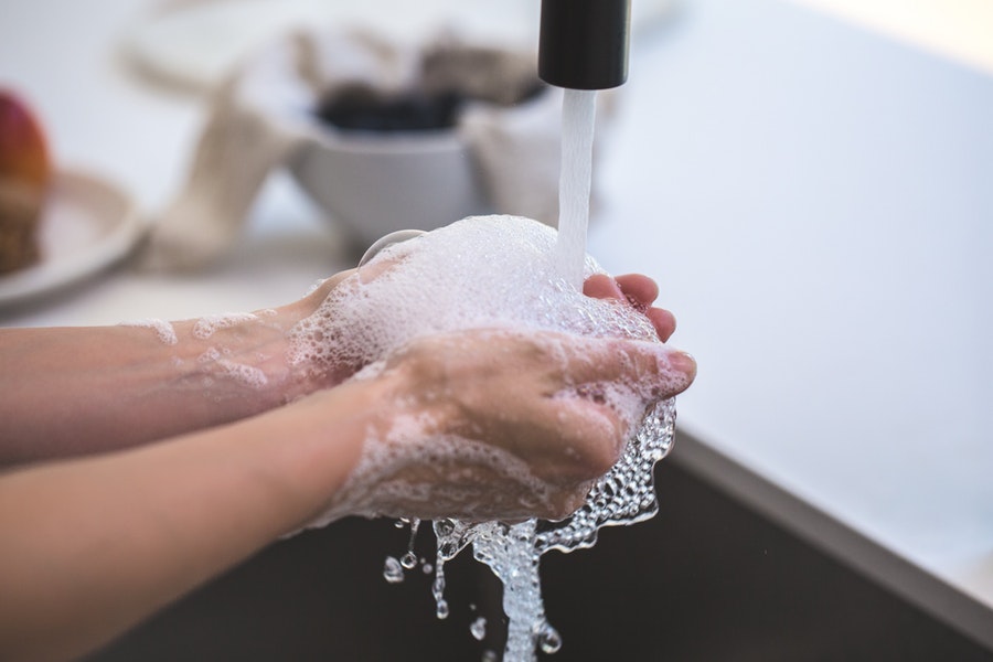 A person is washing their hands at their sink with bubbly water.