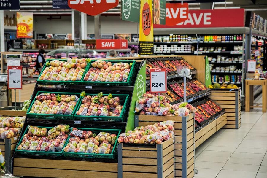 The produce aisle in a grocery store with green crates of apples.