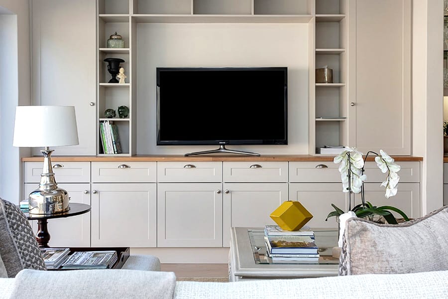 A large flat-screen television is sitting at the center of a cream-colored entertainment center.